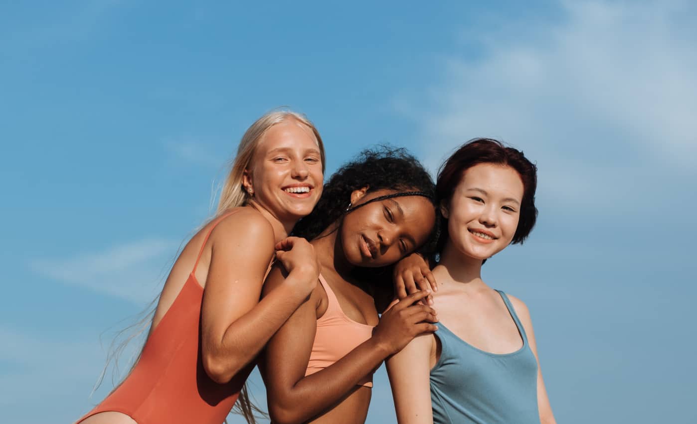 Three women stood together in swimwear showing diversity